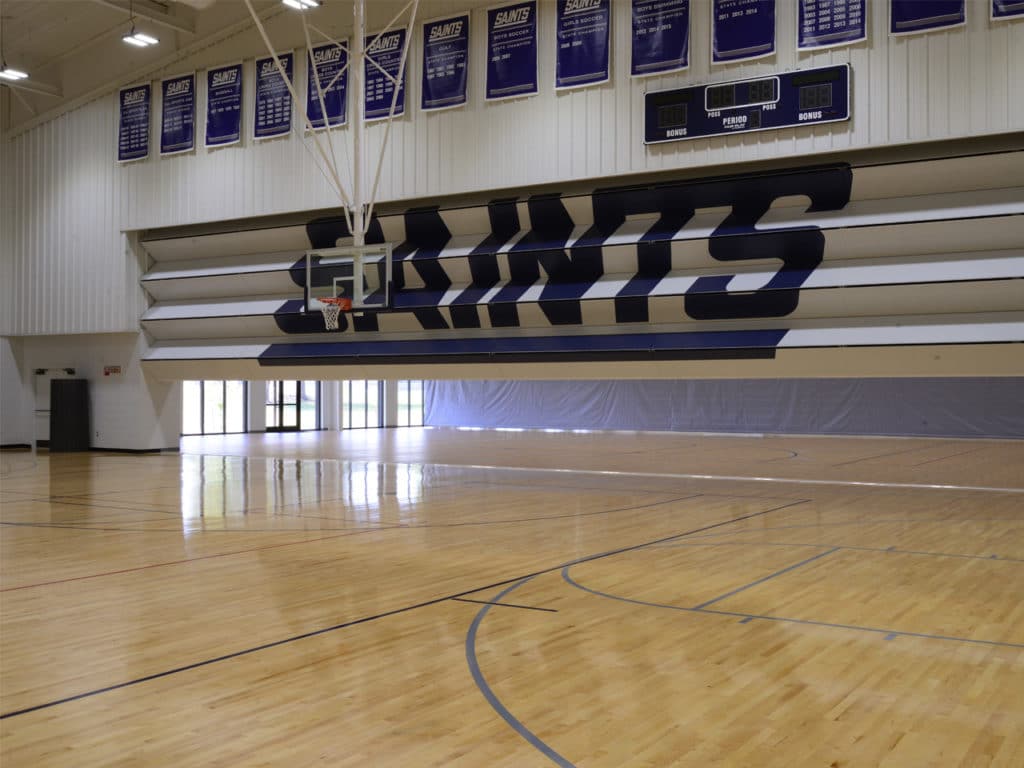 Skyfold Classic operable wall with custom graphics, halfway extended in a high school gym.