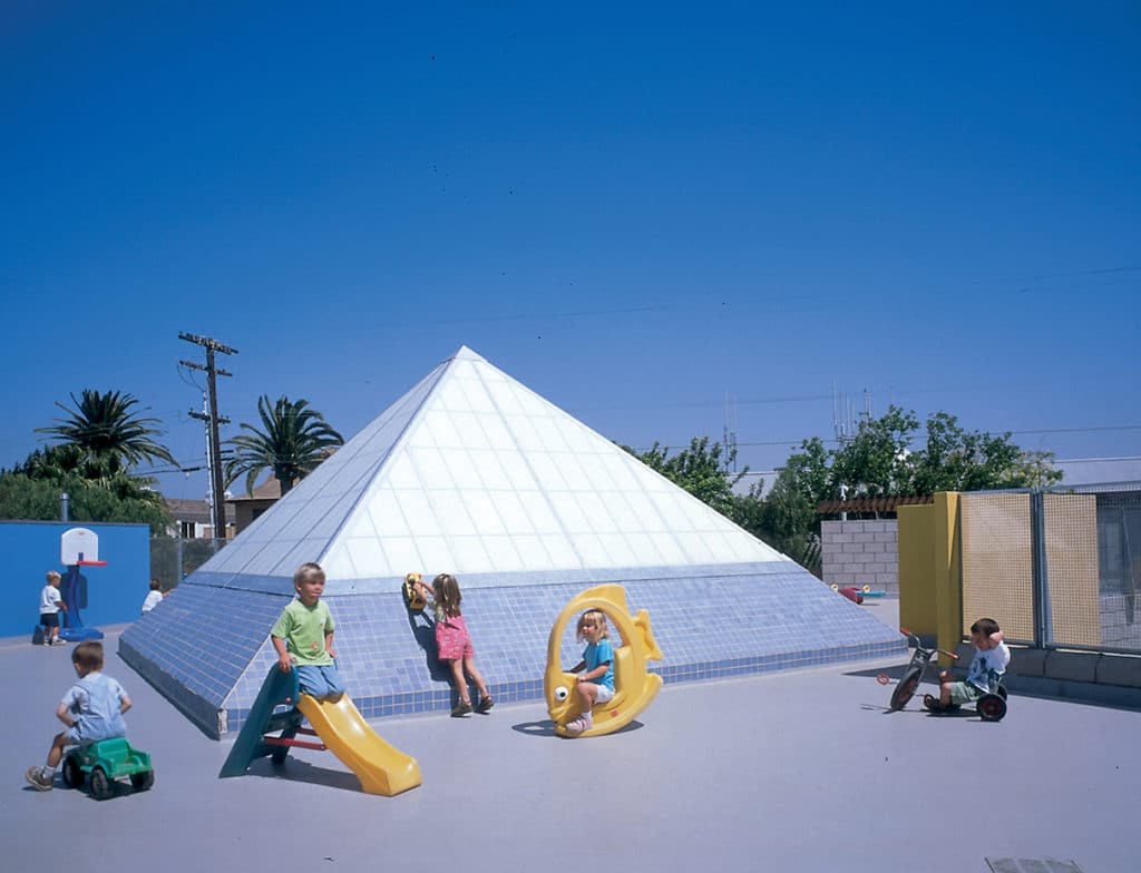 Children playing next to a Kalwall pyramid skylight on the roof of a school.