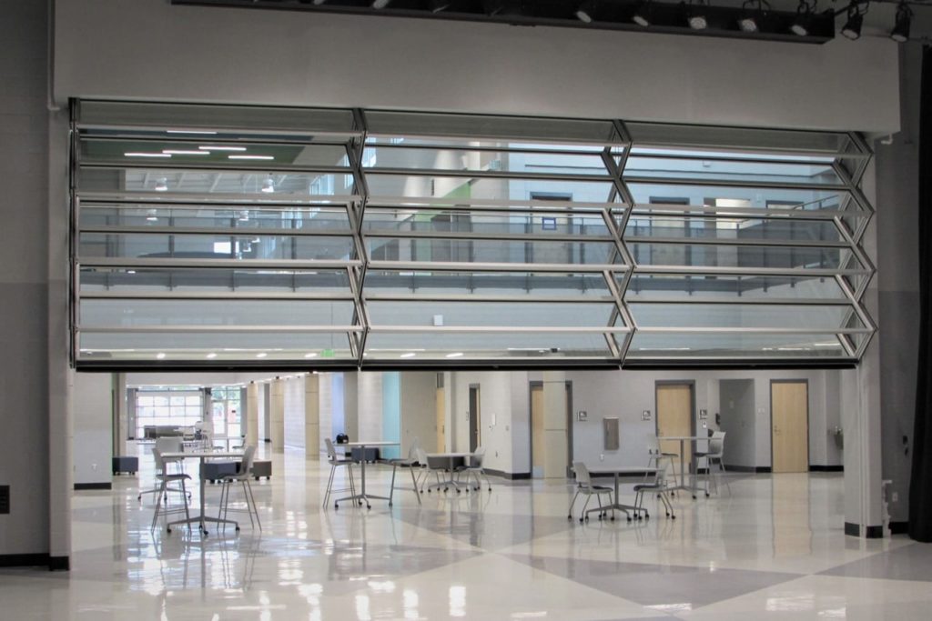 Glass operable wall half-extended in a school interior courtyard.